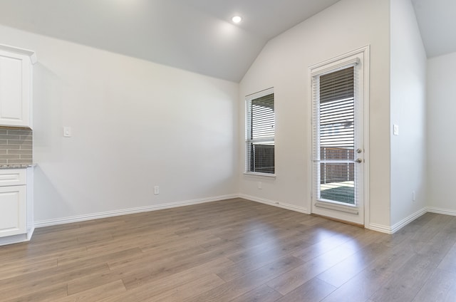 unfurnished dining area with light hardwood / wood-style floors and lofted ceiling