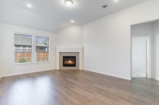 unfurnished living room with a fireplace, light wood-type flooring, and lofted ceiling