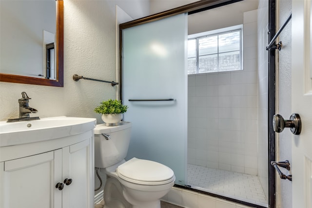 bathroom with a shower with door, vanity, and toilet