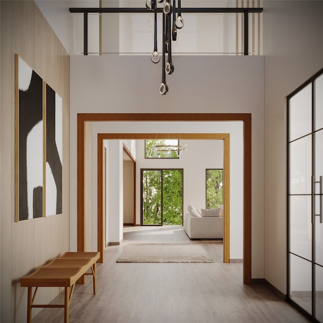 interior space with light wood-type flooring, a towering ceiling, and an inviting chandelier