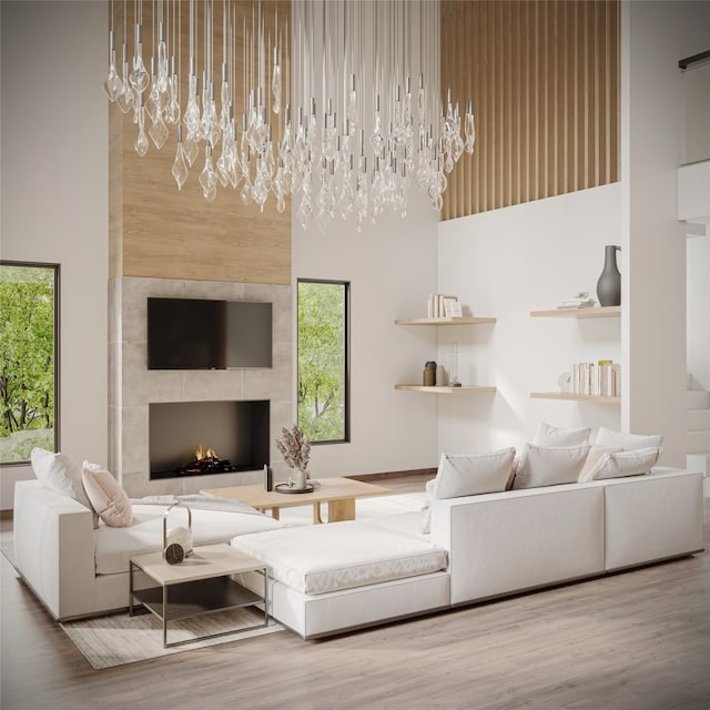 living room with a tiled fireplace, hardwood / wood-style floors, a high ceiling, and an inviting chandelier