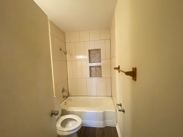 bathroom featuring hardwood / wood-style flooring, toilet, and tiled shower / bath