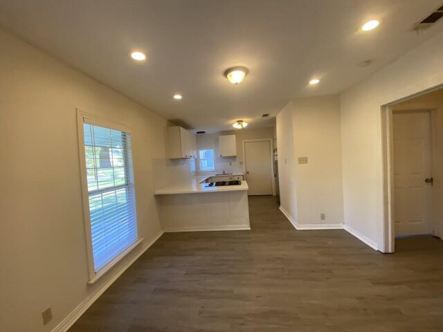 kitchen with white cabinets, dark hardwood / wood-style flooring, and kitchen peninsula