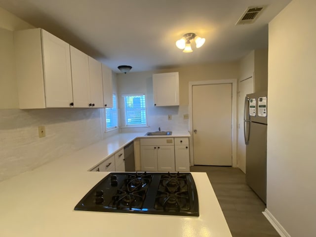 kitchen with backsplash, white cabinets, sink, dark hardwood / wood-style floors, and stainless steel appliances