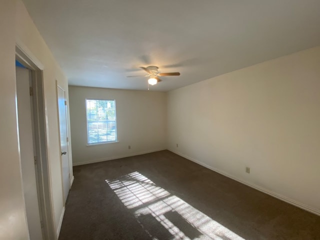 empty room featuring dark carpet and ceiling fan