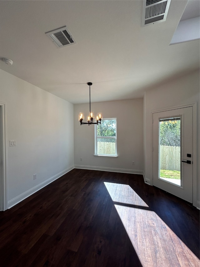 unfurnished dining area with plenty of natural light, dark hardwood / wood-style flooring, and an inviting chandelier