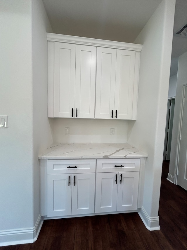 bar featuring light stone counters, dark hardwood / wood-style flooring, and white cabinets