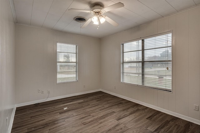 empty room with dark hardwood / wood-style floors, a healthy amount of sunlight, crown molding, and ceiling fan