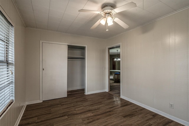 unfurnished bedroom featuring ornamental molding, ceiling fan with notable chandelier, a closet, and dark wood-type flooring