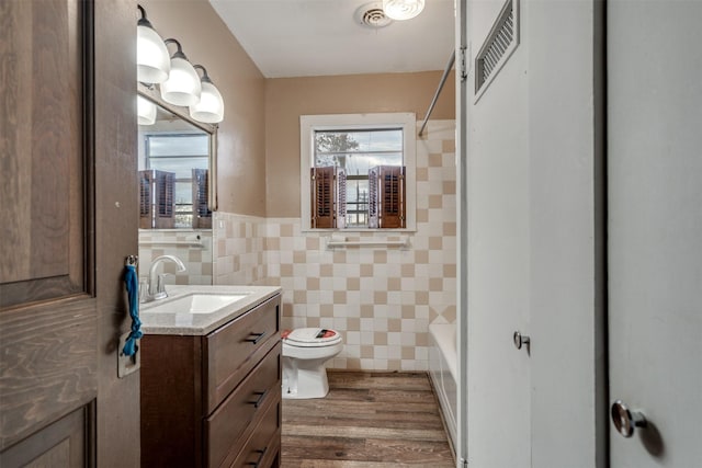 full bathroom with shower / bathtub combination, vanity, hardwood / wood-style flooring, tile walls, and toilet