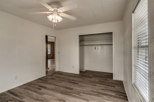 unfurnished bedroom with ceiling fan, dark hardwood / wood-style flooring, ornamental molding, and a closet