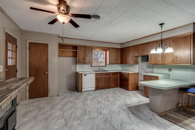 kitchen with kitchen peninsula, ceiling fan with notable chandelier, white dishwasher, sink, and hanging light fixtures