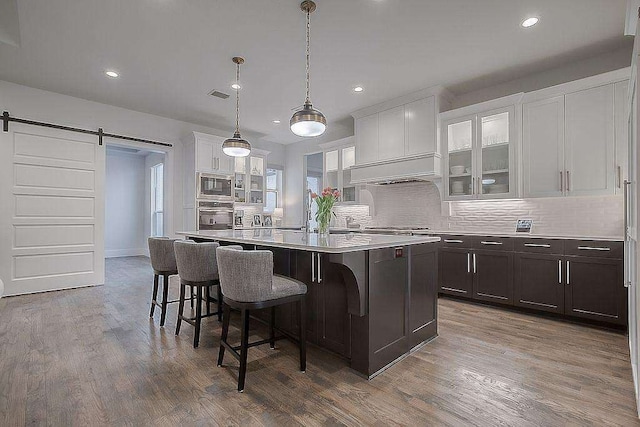 kitchen with a barn door, hardwood / wood-style floors, a kitchen island, and stainless steel appliances