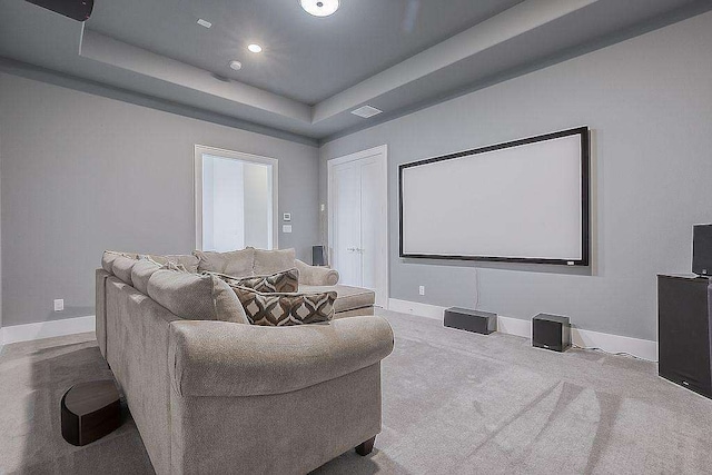 home theater featuring light carpet and a tray ceiling