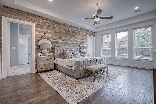 bedroom with wood-type flooring, ceiling fan, and wood walls