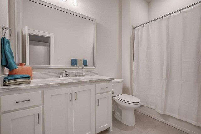 full bathroom featuring tile patterned floors, shower / tub combo with curtain, vanity, and toilet