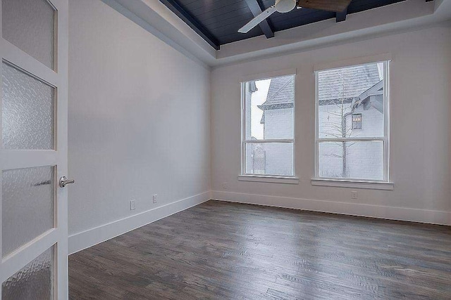 empty room featuring ceiling fan, dark hardwood / wood-style flooring, and a tray ceiling