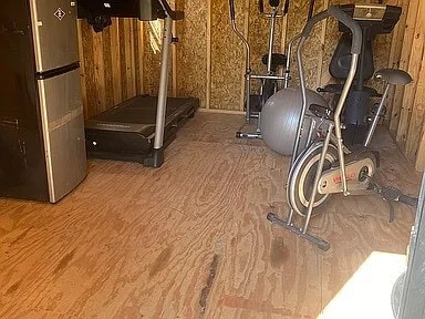 workout room with wood walls and hardwood / wood-style flooring