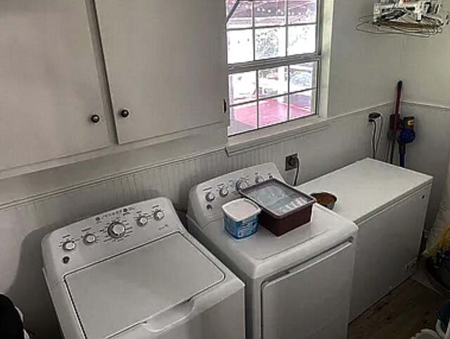 laundry room featuring washing machine and clothes dryer and cabinets