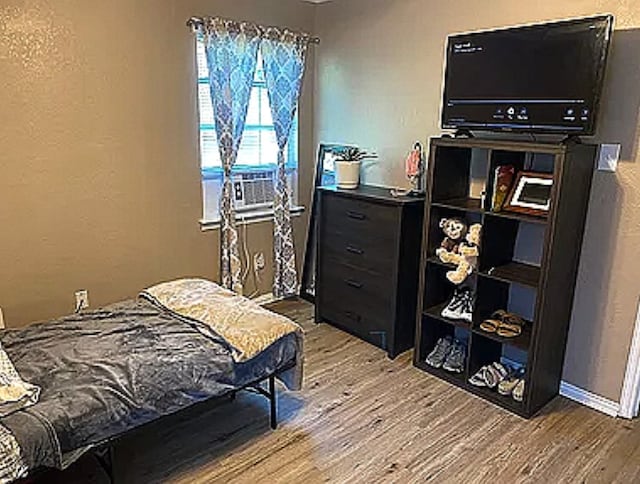 bedroom with hardwood / wood-style floors and cooling unit