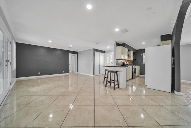 kitchen featuring white cabinets, a kitchen bar, ornamental molding, and stainless steel stove