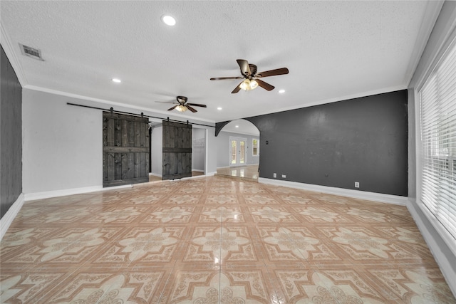 unfurnished living room featuring a barn door, crown molding, ceiling fan, and a textured ceiling