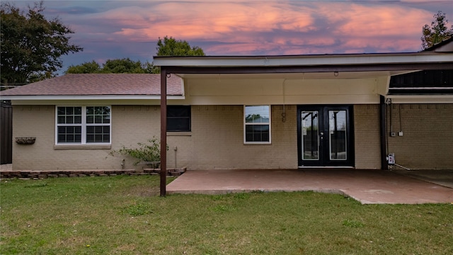 back house at dusk with a yard and a patio