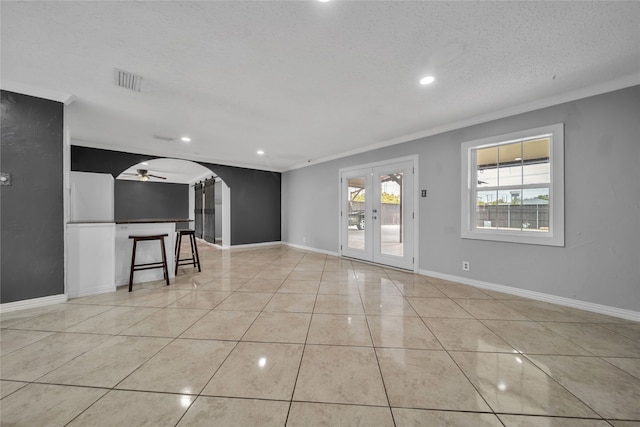 unfurnished room with ceiling fan, french doors, a textured ceiling, light tile patterned floors, and ornamental molding