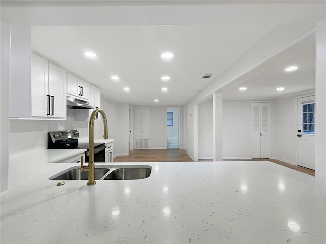 kitchen with electric range, visible vents, light stone countertops, under cabinet range hood, and white cabinetry