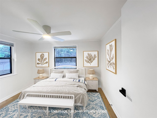 bedroom with ceiling fan, crown molding, baseboards, and wood finished floors