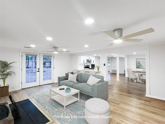 living room with ceiling fan, french doors, light hardwood / wood-style floors, and sink