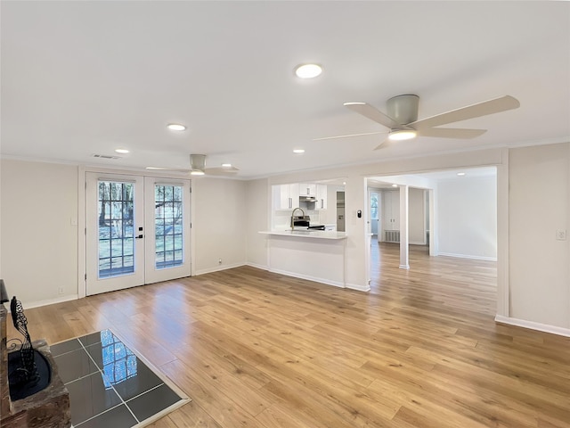 unfurnished living room featuring ceiling fan, french doors, ornamental molding, and light wood-style flooring