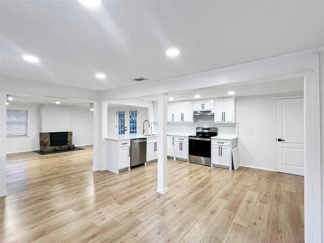 kitchen with stainless steel electric range oven, sink, and white cabinets