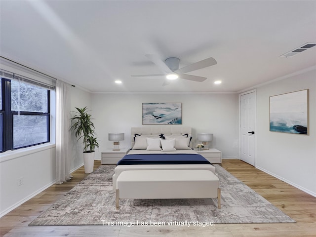 bedroom with visible vents, crown molding, and light wood-style flooring