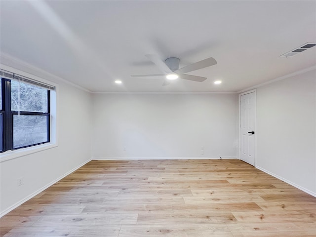 empty room with visible vents, crown molding, and light wood finished floors