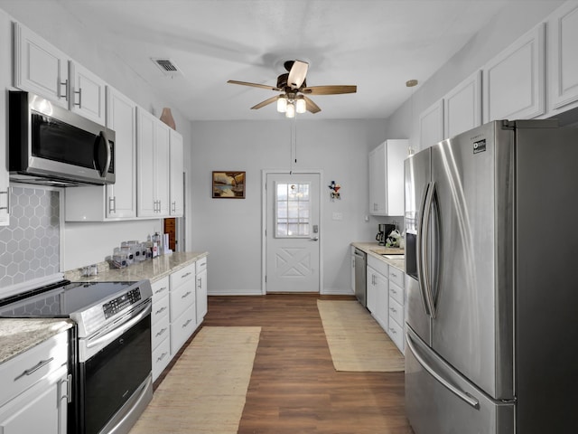 kitchen featuring backsplash, hardwood / wood-style flooring, appliances with stainless steel finishes, light stone counters, and white cabinetry