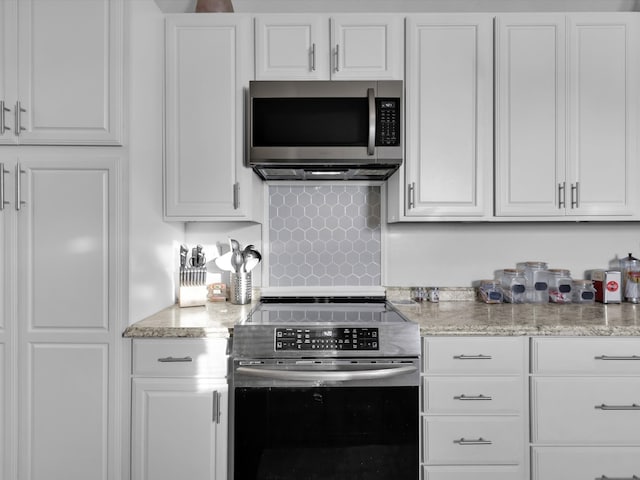 kitchen featuring backsplash, light stone counters, white cabinetry, and stainless steel appliances