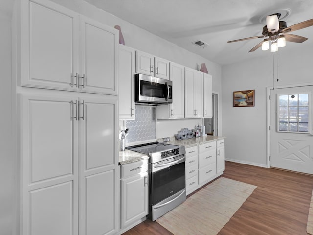 kitchen with light hardwood / wood-style flooring, decorative backsplash, light stone counters, white cabinetry, and stainless steel appliances