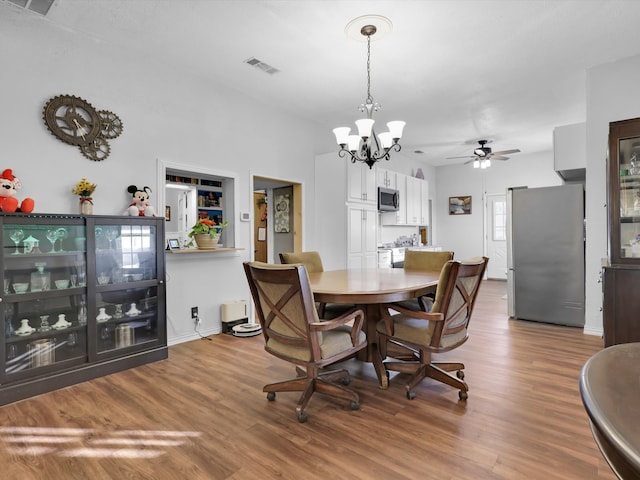 dining space with ceiling fan with notable chandelier and wood-type flooring