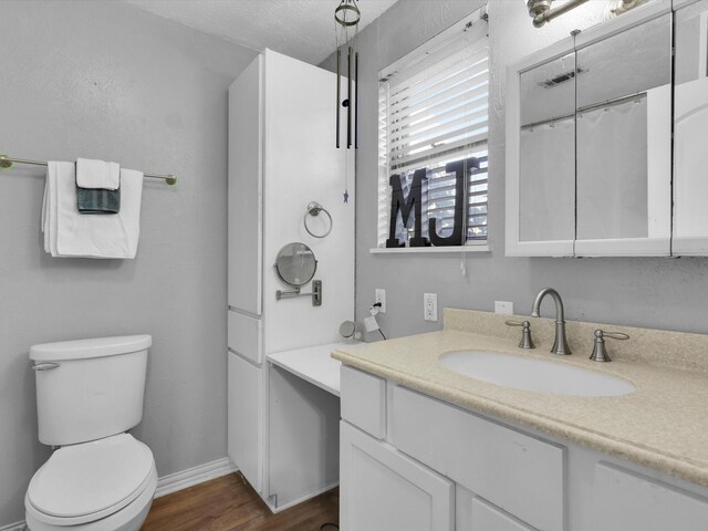 bathroom featuring hardwood / wood-style floors, vanity, a textured ceiling, and toilet