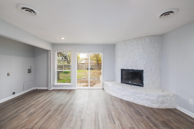 unfurnished living room featuring a stone fireplace and hardwood / wood-style floors