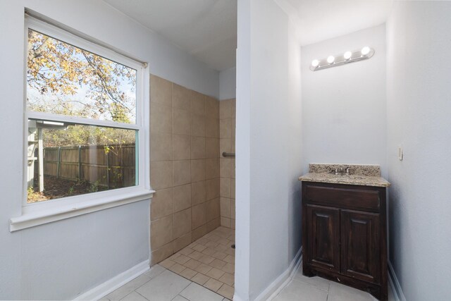 bathroom featuring tile patterned flooring, vanity, and tiled shower