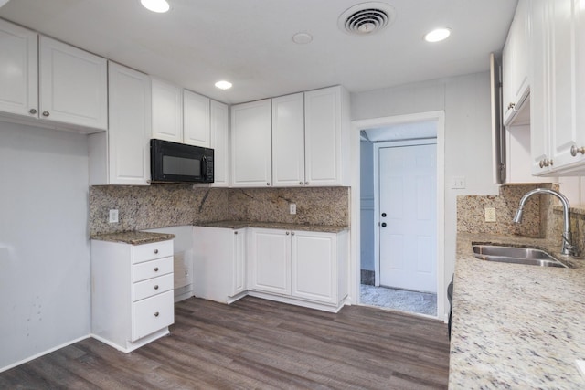 kitchen with backsplash, sink, white cabinetry, and dark wood-type flooring