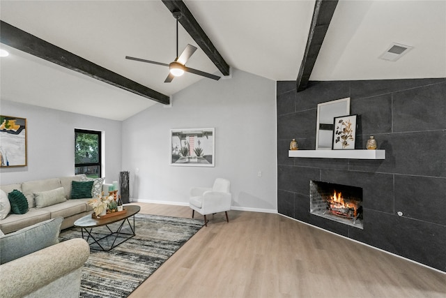 living room with ceiling fan, a fireplace, lofted ceiling with beams, and hardwood / wood-style floors