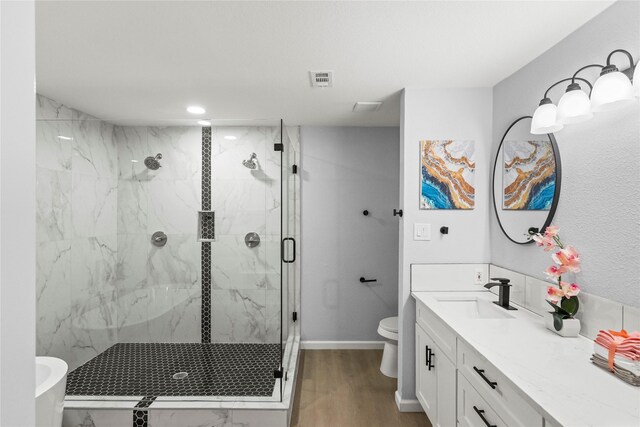 bathroom with hardwood / wood-style floors, vanity, toilet, and a shower with door