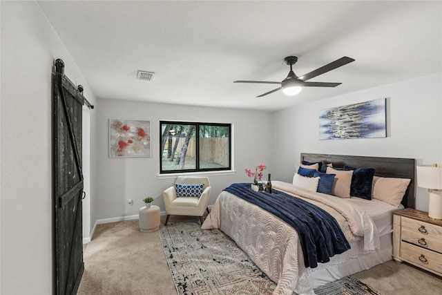 carpeted bedroom featuring ceiling fan and a barn door