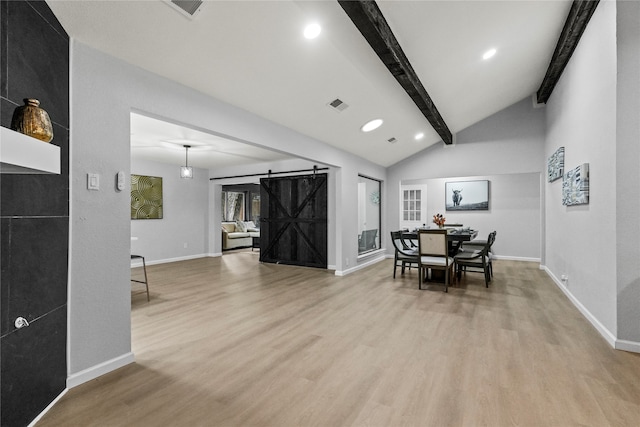 dining area featuring vaulted ceiling with beams, a barn door, and light hardwood / wood-style floors