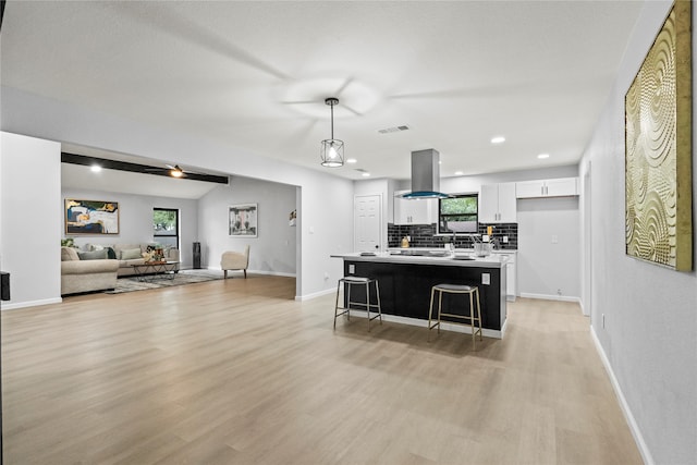 kitchen featuring island exhaust hood, light hardwood / wood-style floors, white cabinetry, and hanging light fixtures