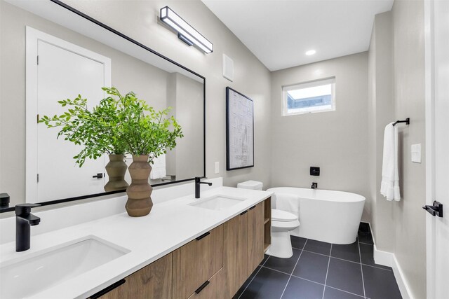 bathroom featuring toilet, a washtub, vanity, and tile patterned flooring