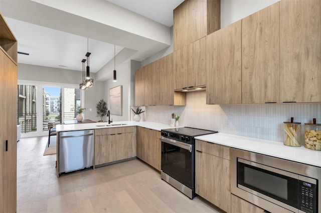 kitchen with sink, light hardwood / wood-style flooring, kitchen peninsula, pendant lighting, and appliances with stainless steel finishes